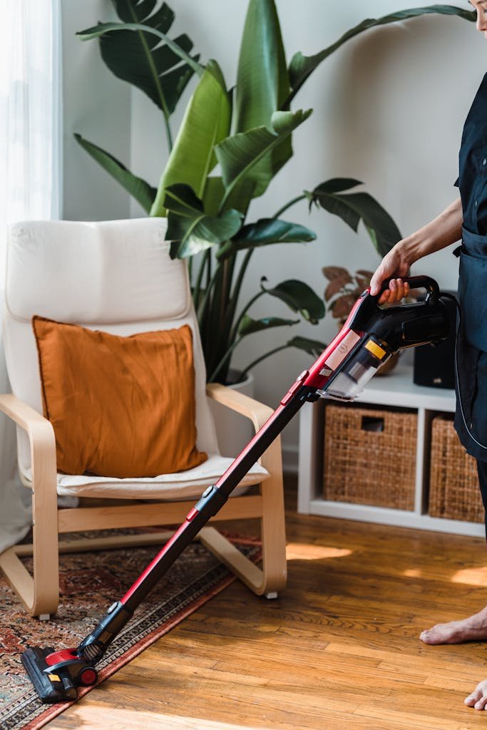 Person in Black T-shirt and Black Pants Holding Black and Red Vacuum Cleaner