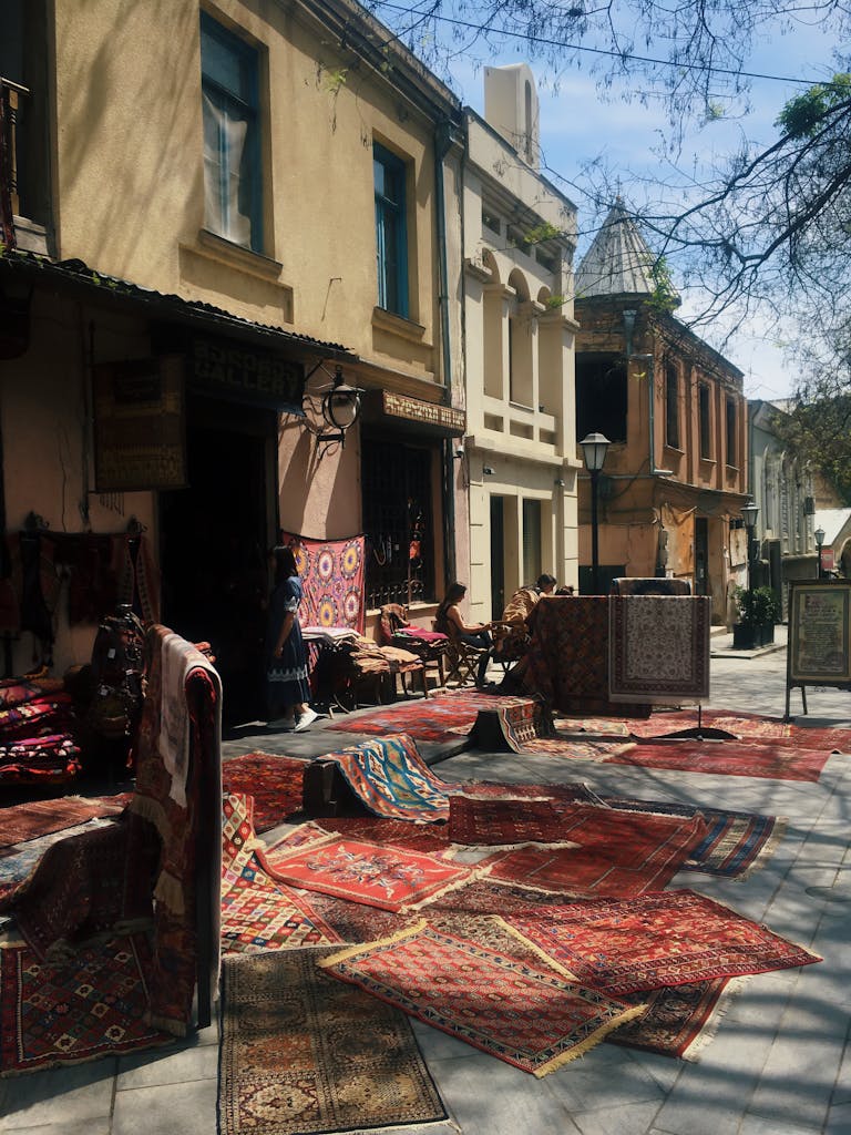 Charming street scene in Tbilisi showcasing traditional carpets outside shops on a sunny day.