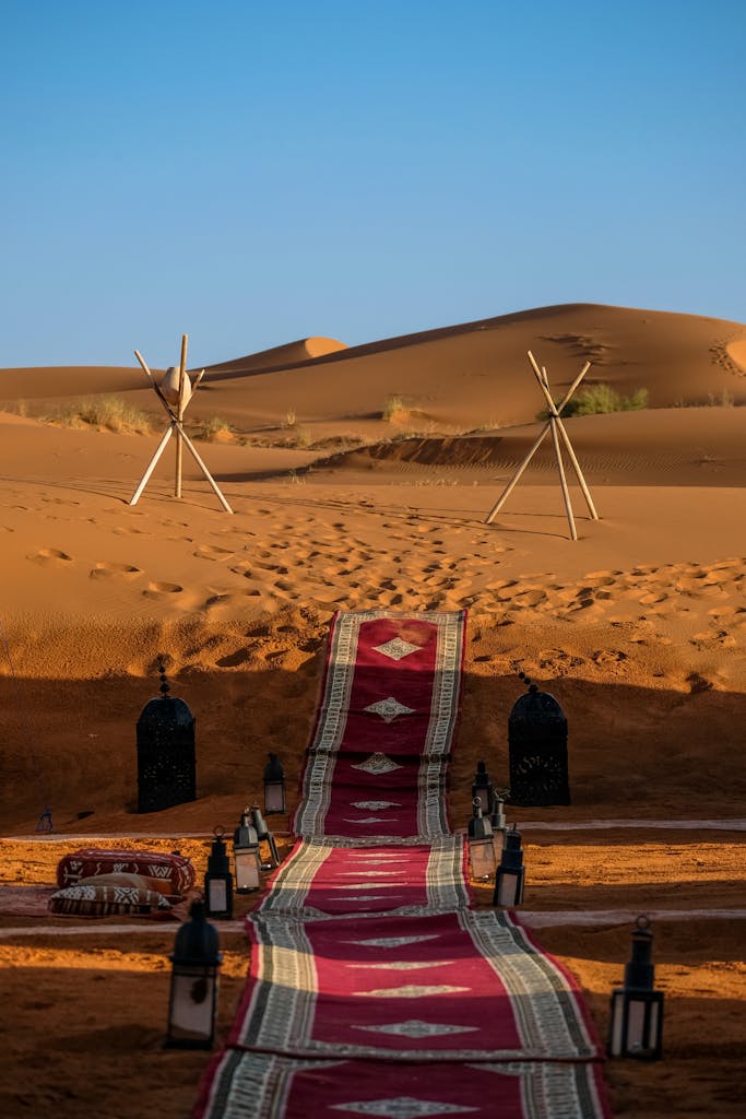 Explore the stunning sunset in Merzouga, Morocco with a vibrant rug's pathway through the dunes.