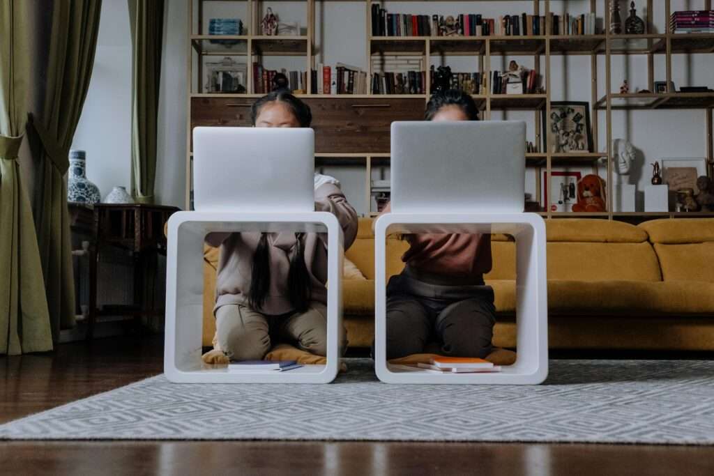 two women sitting on the floor with laptops